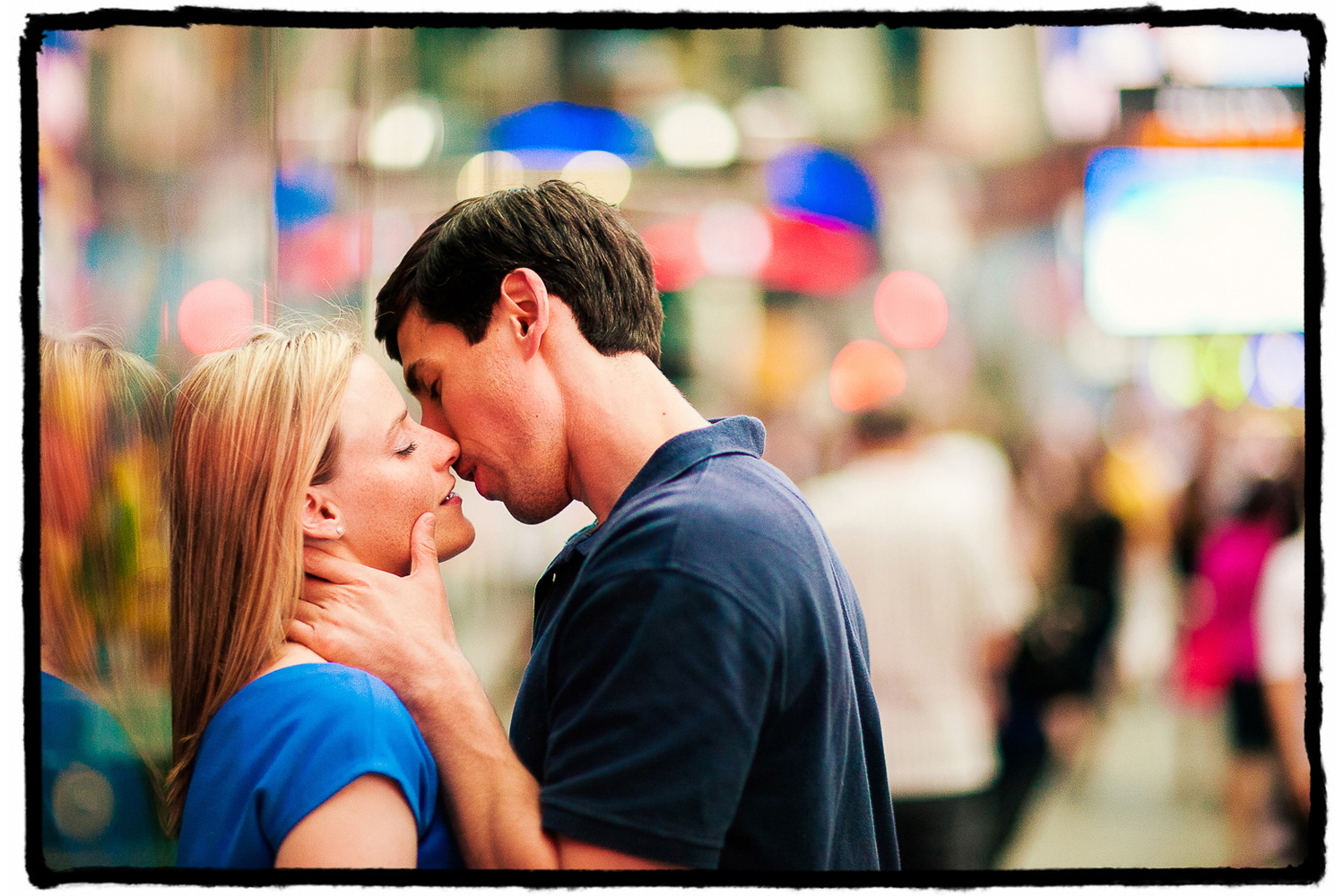 Engagement Portrait: Seth kisses Jennifer in a romantic moment amidst the activity and color of Times Square.