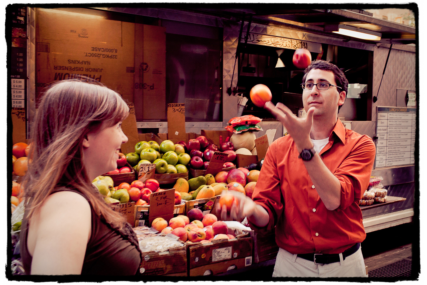 Engagement Portraits: Jason proves to Katie that he can in fact juggle at a fruit stand in manhattan.