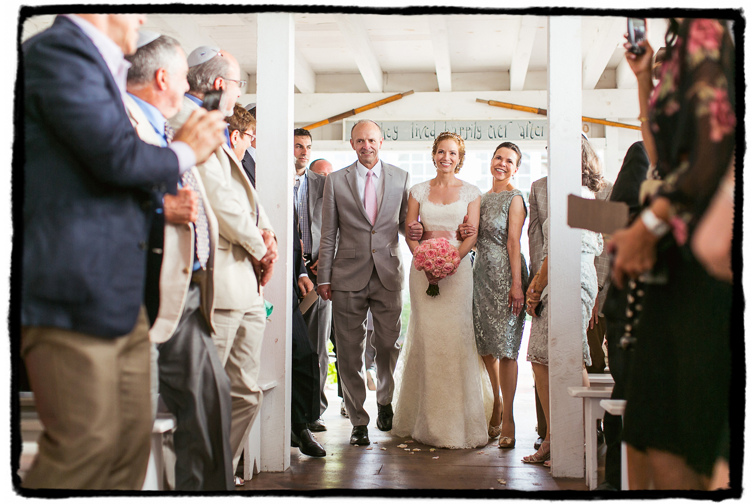 Kelly is walked down the aisle by her parents in the seaside chapel at Bonnet Island Estate.