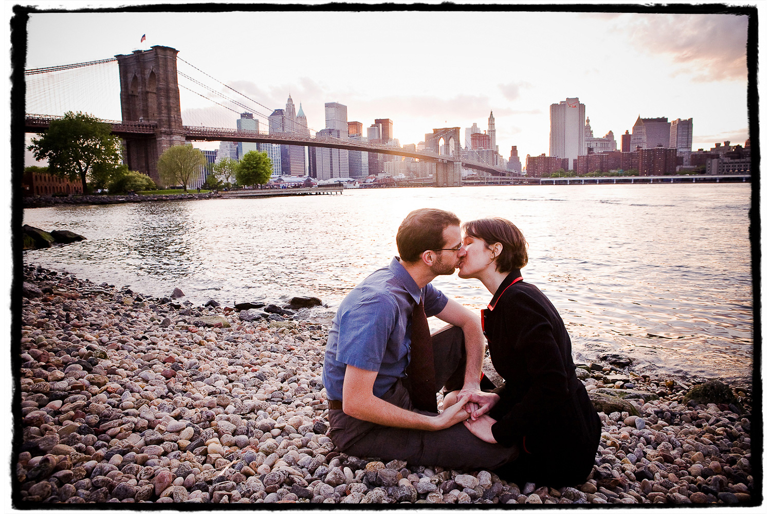 Engagement Portraits: Lindsay & Ben share a kiss on the pebbled beach in DUMBO, Brooklyn.